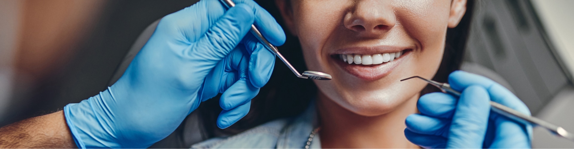 Médico dentista explorando la boca de una paciente sonriente